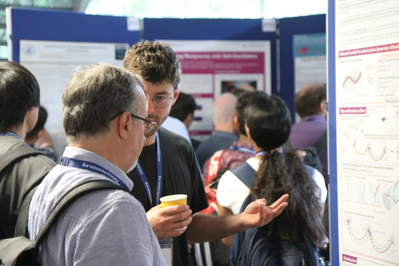 Two researchers in discussion during a poster session at META 2026, Trinity College Dublin